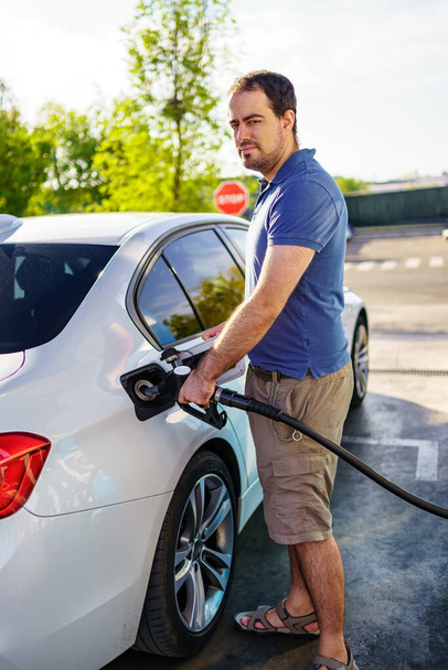 Young man refueling with high prices due to global inflation - 写真・画像
