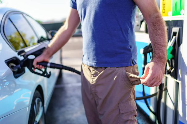 Людина з порожніми кишенями в знак високих цін на паливо на АЗС
 - Фото, зображення