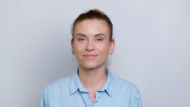 Portrait of a smiling young woman in a shirt on a white background. Happy girl manager looks at the camera. - Záběry, video