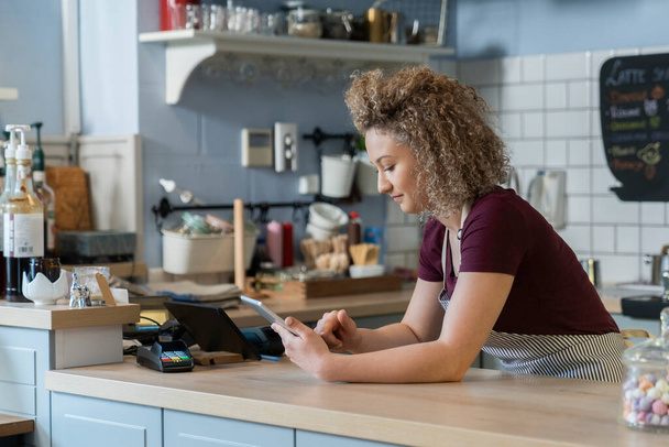 Jovem garçonete caucasiana usando tablet digital no trabalho no café - Foto, Imagem