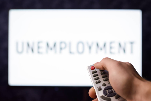 Unemployed man watching TV switching a TV set off with inscription UNEMPLOYMENT - Foto, imagen