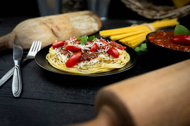 Italian spaghetti pasta with tomato sauce, parmesan cheese and basil served on the plate on rustic kitchen table - Photo, image