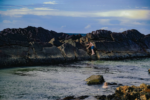 Kids climbing rock wall at The Tanks tourist attraction natural rock pool at Forster, NSW Australia - Foto, afbeelding