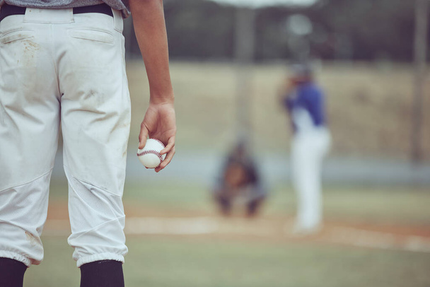 Baseball player holding ball during a game on the field. Man concentrating before throwing a ball at a sports match. Professional athlete getting ready to throw the ball during a competitive game - Foto, imagen