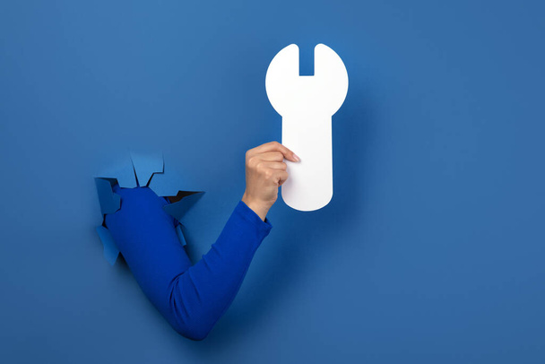 hand holding wrench over blue background - Fotoğraf, Görsel