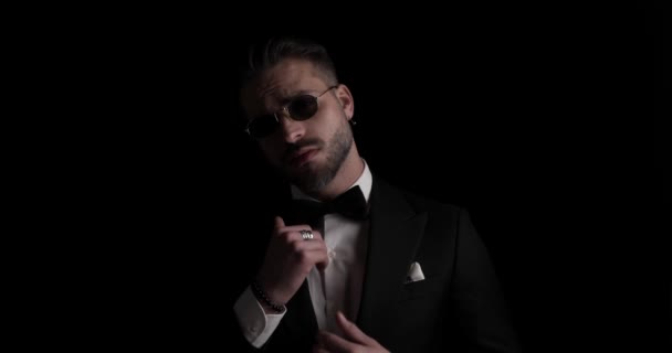 mysterious sexy groom rubbing palms, looking to side, adjusting tuxedo and sunglasses and crossing arms in the dark - Video