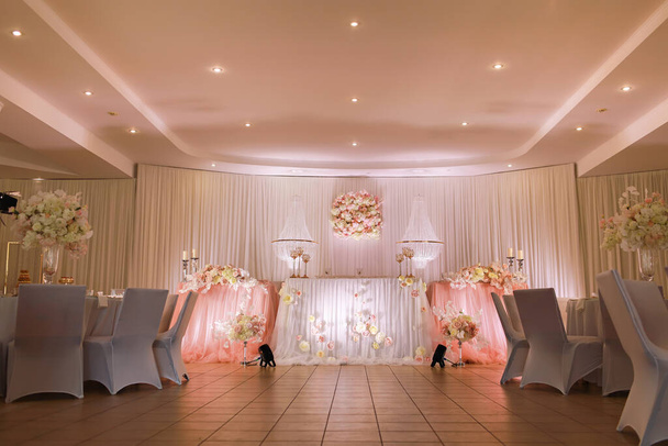 festliche Tischdekoration mit Kristallleuchtern, goldenen Kerzenleuchtern, Kerzen und weiß-rosa Blumen. Stilvoller Hochzeitstag. - Foto, Bild