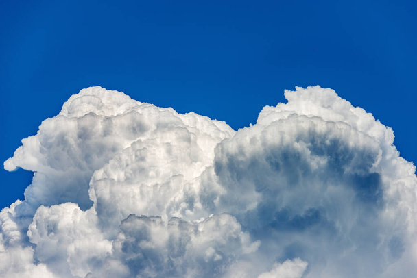Φωτογραφία από όμορφα σύννεφα καταιγίδας, πυκνά σύννεφα ή cumulonimbus ενάντια σε ένα καθαρό γαλάζιο ουρανό. Πλήρες πλαίσιο, ουρανός μόνο. - Φωτογραφία, εικόνα