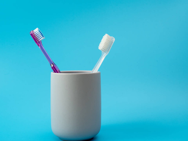 Cepillos de dientes en un vaso con espacio para copiar sobre un fondo azul. - Foto, imagen