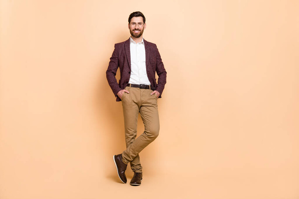Full size image of young good looking handsome businessman hold hands in pockets isolated on beige color background. - Fotografie, Obrázek
