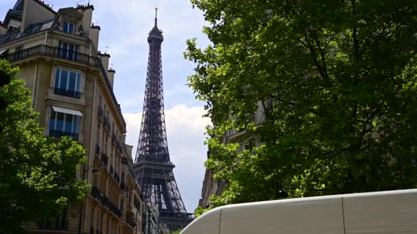 Paris, Frankreich. Juni 2022. Erstaunliche Aufnahmen des Eiffelturms, der zwischen den Gebäuden des historischen Zentrums und den Baumkronen hervorsticht. Ein weißer Lieferwagen fährt an der Ampel vorbei. - Filmmaterial, Video