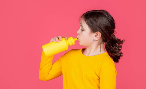 thirsty kid drinking water on pink background. - Foto, immagini