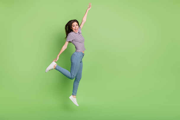 Full length body size view of attractive cheerful lucky girl jumping stretching isolated on bright green color background. - Photo, image