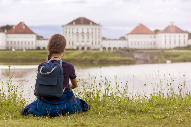 Travel Europe - European Castle Palace. Girl Traveler looking on Castle Nymphenburg Palace on Lake. Top view on Nymphenburg Palace in Munich with Lake. - Foto, immagini