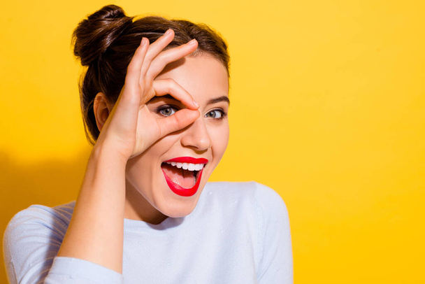 Portrait of young adorable young excited female looking through okay symbol isolated on yellow color background. - 写真・画像