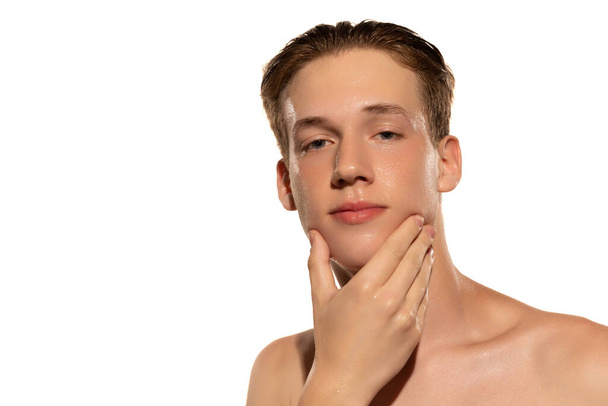 First shaving. Close-up portrait of young handsome man isolated on white studio background. Concept of mens health, self-care, body and skin care. Male model looking at camera - 写真・画像