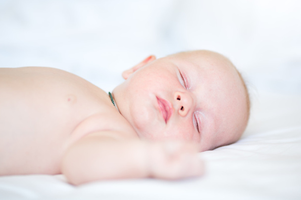 Peaceful newborn baby lying on a bed sleeping - Foto, Bild
