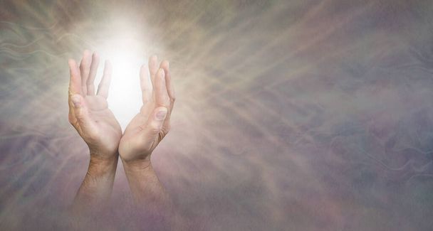 Sending out beautiful gentle healing energy - mature male hands reaching up into white light   against a grey radiating energy web form background with copy space on right - Photo, image