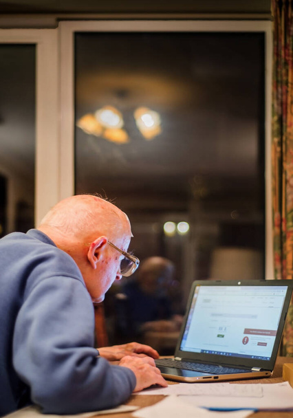 Egy 93 éves öregembernek gondjai vannak a számítógépével, hogy ellenőrizze a pénzügyeit az interneten, ami nagy kihívást jelent az idősek számára.. - Fotó, kép