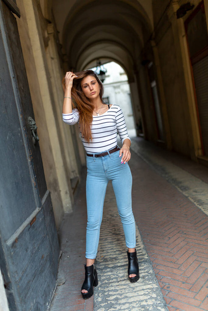 beautiful brunette Italian girl poses in front of an old door. High quality photo - Photo, image