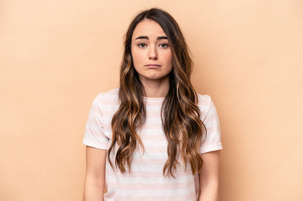 Young caucasian woman isolated on beige background sad, serious face, feeling miserable and displeased. - Foto, afbeelding