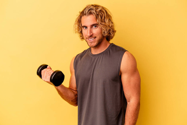 Young sport man making weightlifting isolated on yellow background - Photo, image