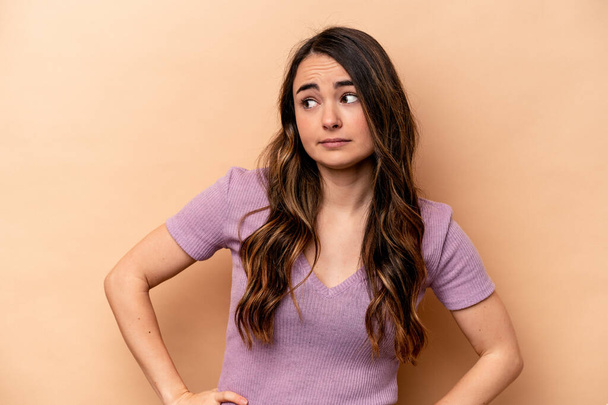 Young caucasian woman isolated on beige background confused, feels doubtful and unsure. - Photo, Image