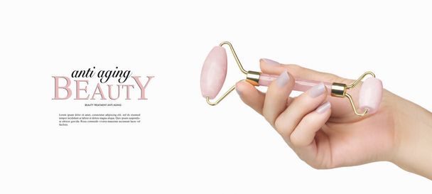 Banner publicitario de belleza y cuidado de la piel con rodillo de cuarzo rosa en mano femenina aislado en blanco con copyspace - Foto, Imagen