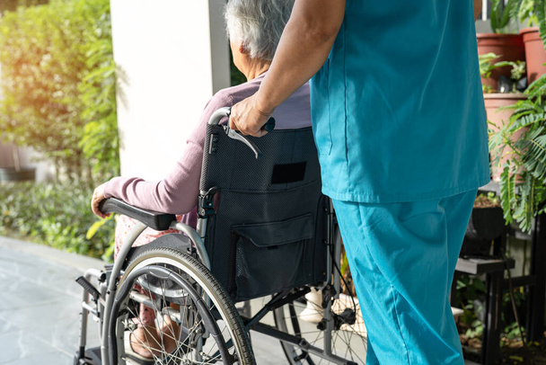 Huoltaja apua ja hoitoa Aasian vanhempi tai vanhusten vanha nainen nainen potilas istuu pyörätuolilla rampilla hoitotyön sairaalassa, terve vahva lääketieteellinen käsite - Valokuva, kuva
