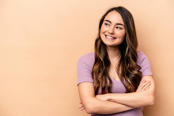 Young caucasian woman isolated on beige background smiling confident with crossed arms. - 写真・画像