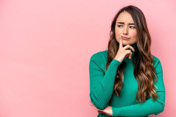 Young caucasian woman isolated on pink background looking sideways with doubtful and skeptical expression. - Photo, Image