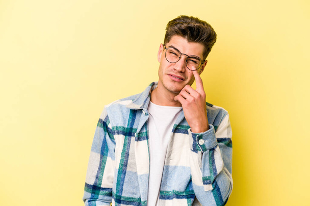 Young caucasian man isolated on yellow background crying, unhappy with something, agony and confusion concept. - Photo, Image