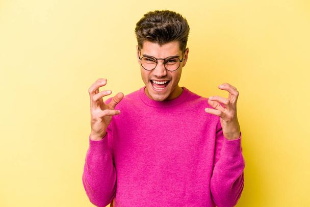 Young caucasian man isolated on yellow background screaming with rage. - Foto, Imagem