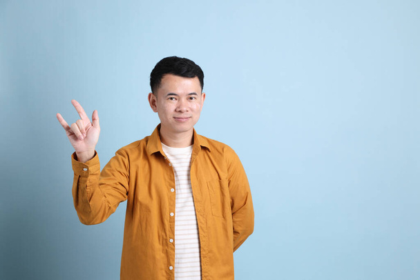 The Asian LGBTQ man with yellow shirt standing on the blue background. - Fotografie, Obrázek