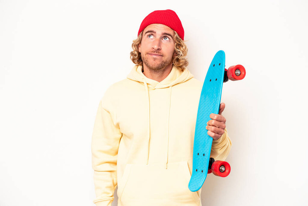 Young skater caucasian man isolated on white background dreaming of achieving goals and purposes - Foto, immagini