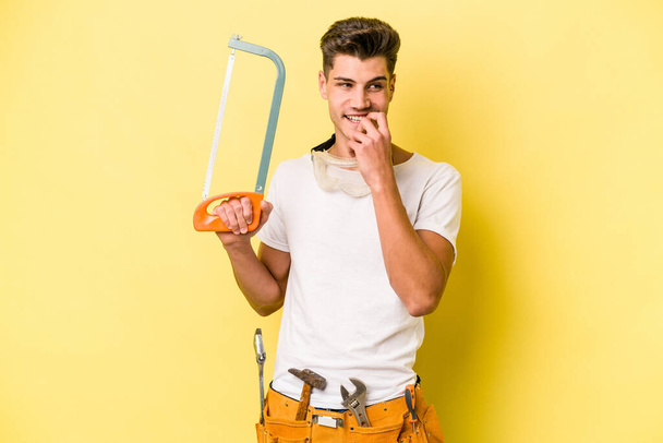 Young electrician caucasian man isolated on yellow backgroun - Foto, afbeelding
