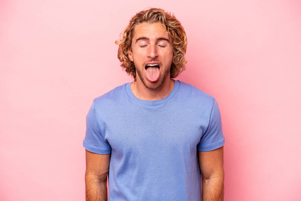 Young caucasian man isolated on pink background funny and friendly sticking out tongue. - Photo, Image