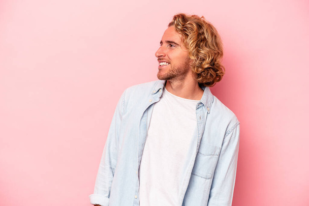 Young caucasian man isolated on pink background relaxed and happy laughing, neck stretched showing teeth. - Fotografie, Obrázek