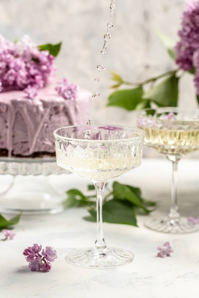 Delicious prosecco, champagne, wine with berry mousse cake bouquet of purple blooming lilacs, French cuisine, postcard, background. - Fotoğraf, Görsel
