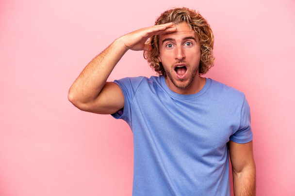 Young caucasian man isolated on pink background shouts loud, keeps eyes opened and hands tense. - Photo, Image