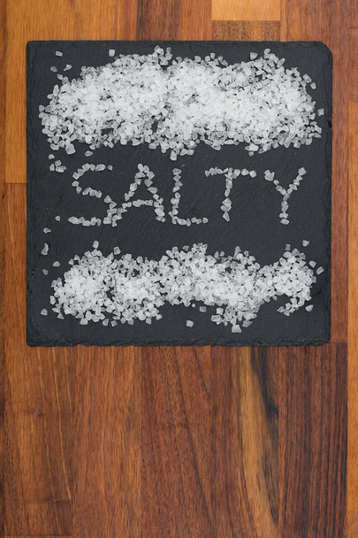 Salt on black plate with wooden background - Photo, Image