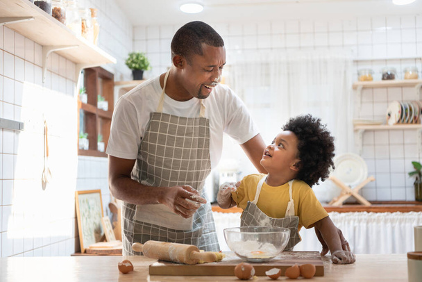 Happy smiling Black African American Father and son playing while doing bakery in kitchen at home. - Photo, image