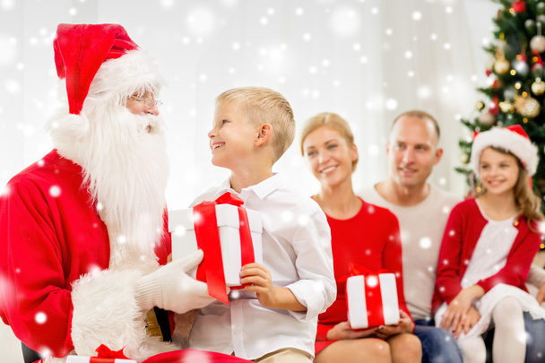 smiling family with santa claus and gifts at home - Foto, afbeelding