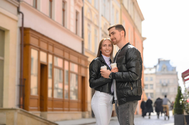 Lovely young couple with cups of coffee together on city street. Romantic date - Fotografie, Obrázek