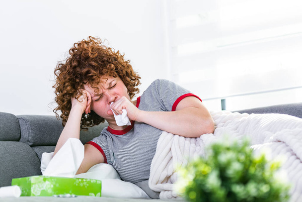 Sick desperate woman has flu. Rhinitis, cold, sickness, allergy concept. Pretty sick woman has runnning nose, rubs nose with handkerchief. Coughing female. - 写真・画像