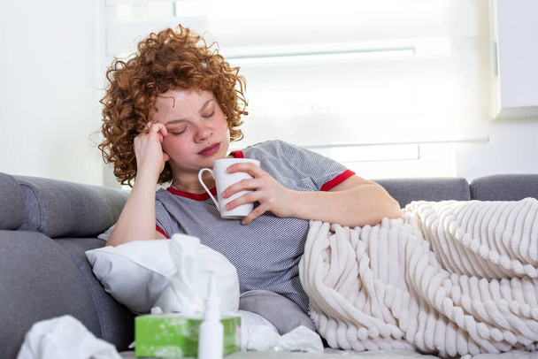Depressed woman laying on a desk with a cup of coffee in hand, Upset depressed young woman lying on couch feeling headache migraine, sad tired drowsy teenager exhausted girl is nervous and stressed - Photo, Image