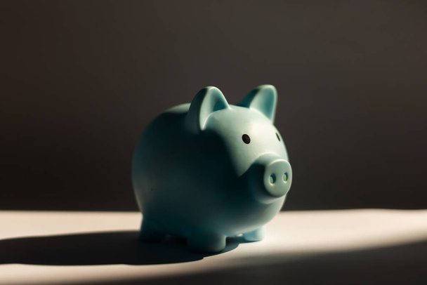 Black piggy bank on table against dark background with space for text. Poverty concept. - Foto, afbeelding