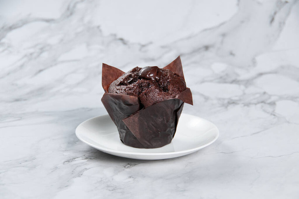 Muffin de chocolate doble servido en una vista lateral plato sobre fondo gris - Foto, Imagen