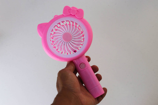 Asian man hand holding a pink handy mini fan isolated on white background - Foto, Bild