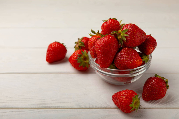 Fresh ripe strawberries in a plate on a white wooden background.Vegetarian organic berry.Healthy food.Vitamins.Copy space.Space for text - Fotó, kép